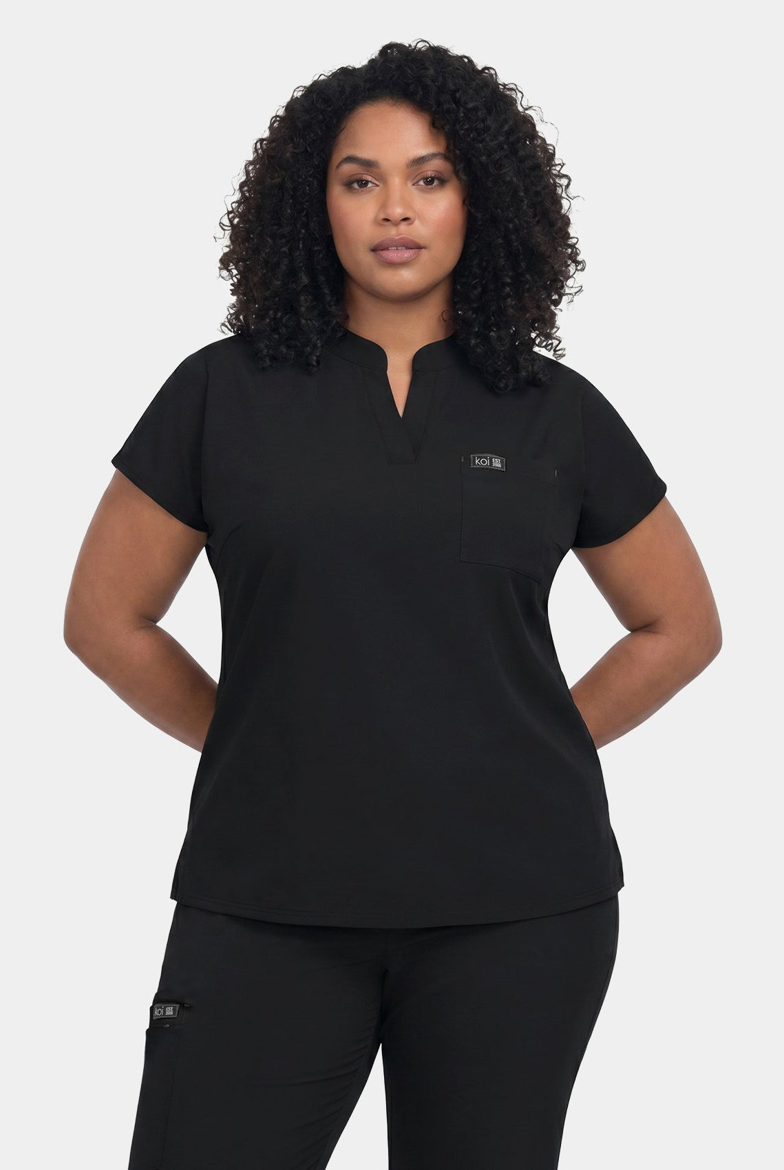 Black women's V-neck scrub top and matching scrub trousers worn by a model, front view.