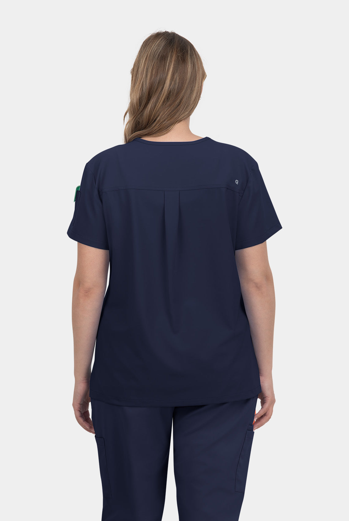 Woman wearing a navy V-neck scrub top shown from the back with short sleeves and centre back pleat.