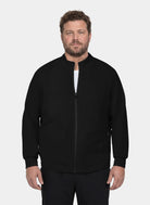 Men's black scrub jacket with stand collar, front zip fastening, long sleeves and front patch pockets, shown on a model.

