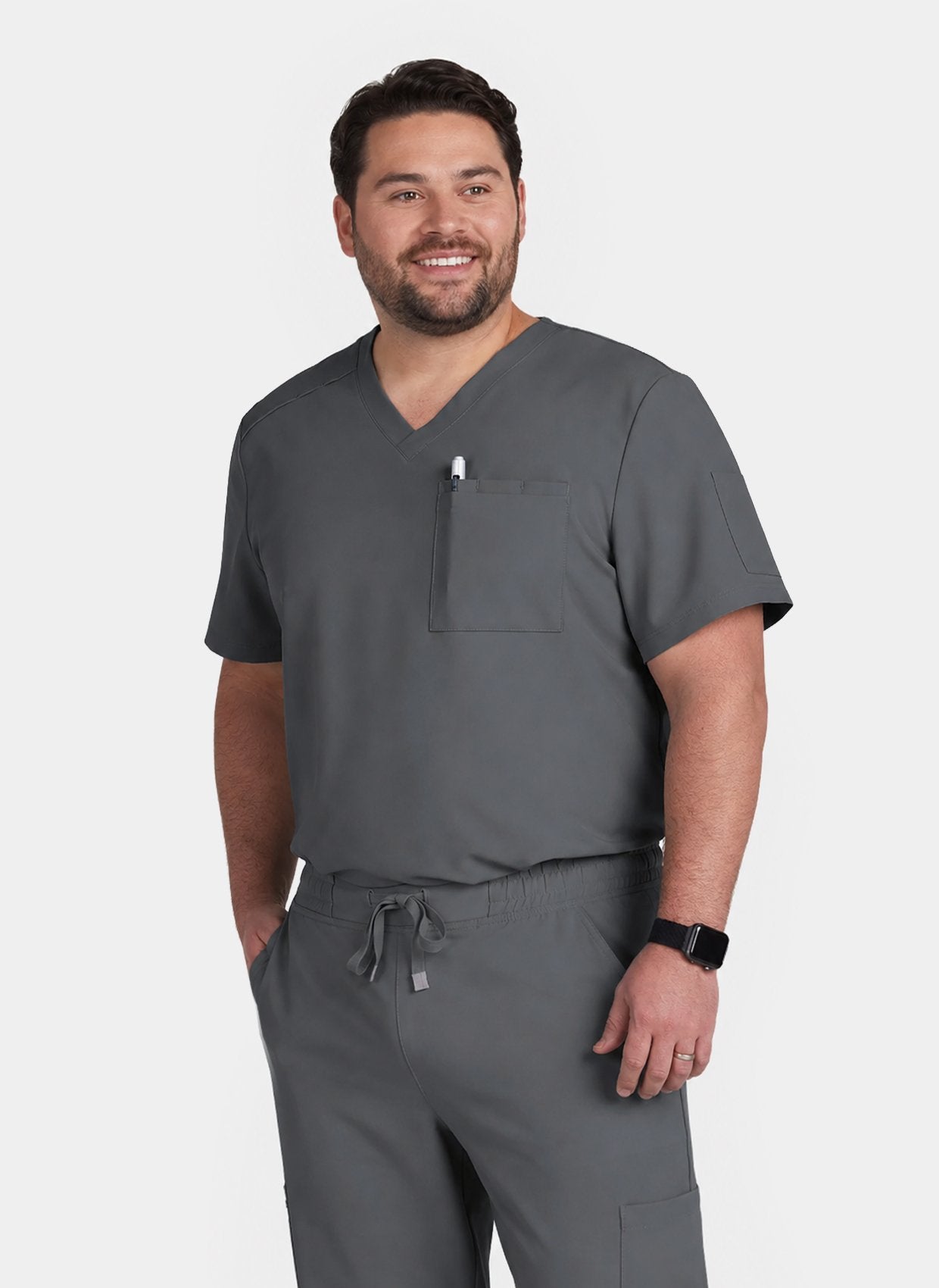Man wearing a grey V-neck scrub top and matching scrub trousers with a chest pocket and drawstring waist.
