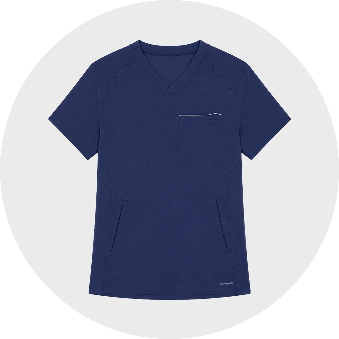 Navy blue Healing Hands scrub top with V-neck, chest pocket with reflective trim, and angled front pockets, laid flat against a gray circular background.