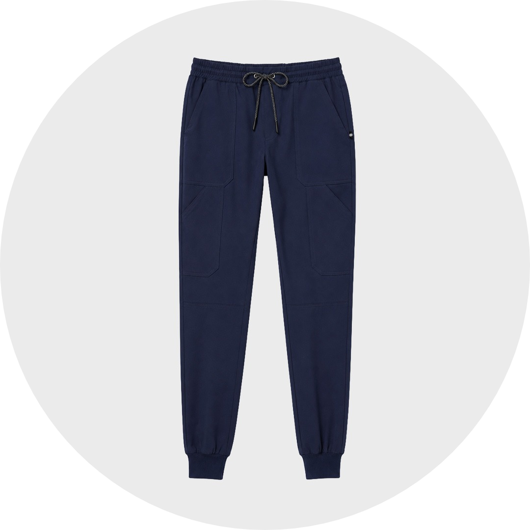 Navy blue jogger scrub trousers with elastic drawstring waist, angled cargo pockets, and ribbed ankle cuffs, laid flat against a gray circular background.