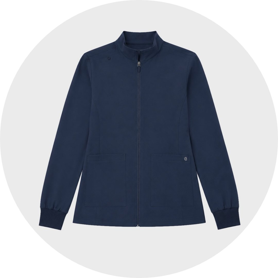 Navy blue koi zip-front scrub jacket with stand collar, two front patch pockets, and ribbed cuffs, laid flat against a gray circular background.