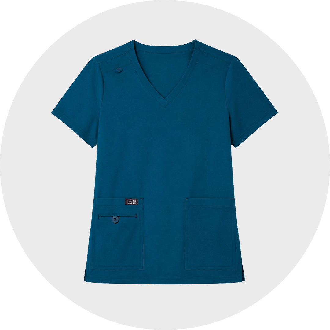 Dark teal short-sleeve koi V-neck scrub top with two lower front patch pockets and a zippered pocket detail, shown flat against a light gray circular background.