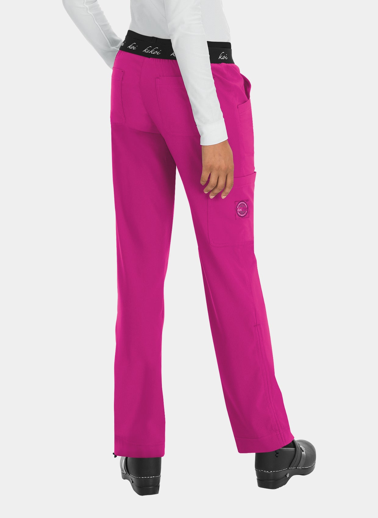 Women's bright pink straight-leg scrub trousers with elastic logo waistband, back patch pockets, and utility pocket, shown from the rear, worn by a model.
